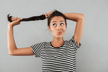 Pretty asian girl playing with her long hair while standing