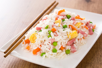 Chinese fried rice with vegetables and omelette on wooden table

