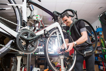 Male involved master is repairing the bicycle in a special workshop