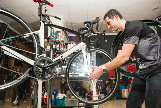 Male involved master is repairing the bicycle in a special workshop