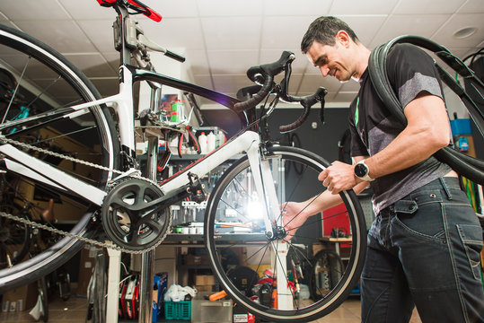 Male involved master is repairing the bicycle in a special workshop