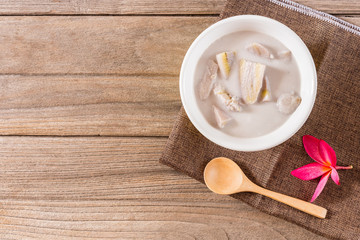 Thai dessert banana in coconut milk on old wooden floor