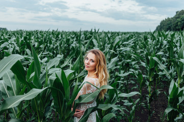 Beautiful girl stands in the field of young corn. Agriculture.