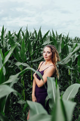 Beautiful girl stands in the field of young corn. Agriculture.