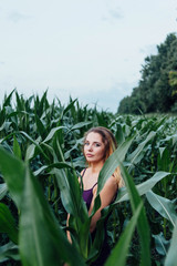 Beautiful girl stands in the field of young corn. Agriculture.