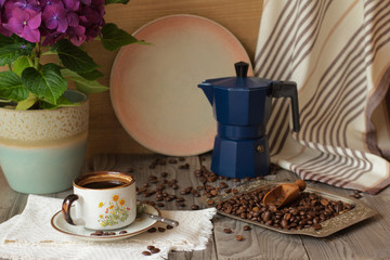 Cup of coffee and coffee pot on a wooden table.
