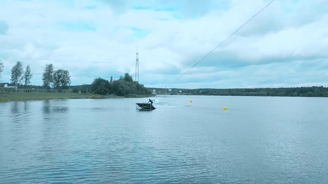 Attractive female practicing wakeboarding tricks in a wakepark near a city. 4K UHD 60 FPS 
