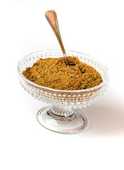 Brown sugar in crystal bowl with silver spoon isolated on white background