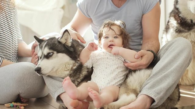 Young mother and father with newborn baby playing with dog