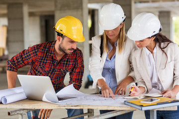 Two female  inspectors and architects discuss with 
 head engineer about construction project.