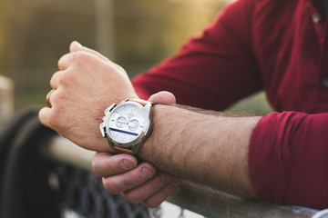 Closeup of young man in casual clothing adjusting wristwatch