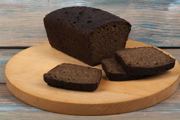 Many mixed breads and rolls of baked bread on wooden table background.