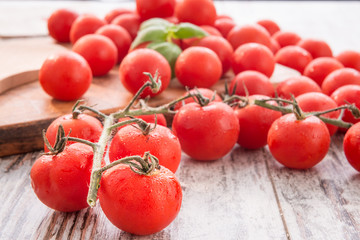 Pomodorini pachino sul tavolo e sul tagliere con foglie di basilico