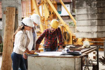 Two female  inspectors and architects discuss with 
 head engineer about construction project.