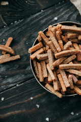 Loaf and crackers with salt on a black wooden background, with the fabric in the composition. Spices and sliced bread