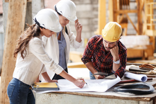 Two female  inspectors and architects discuss with 
 head engineer about construction project.