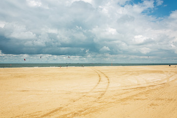 Kytesurfers on the beach of Scheveningen with in the background the seagoing ships at anchor waiting to enter the port of Rotterdam in The Netherlands