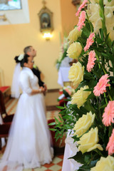 Młoda para przed ołtarzem, piękne kwiaty w kościele.
