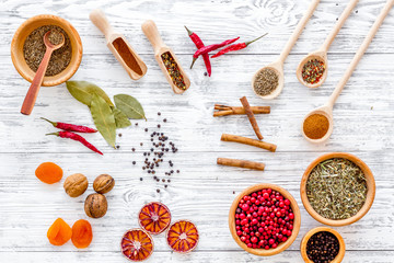 Fototapeta na wymiar Variety of spices and dry herbs in bowls on wooden kitchen table background top view pattern