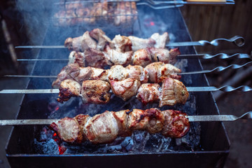 Grilled kebab cooking on metal skewers (grill). Roasted meat cooked at barbecue with smoke. Close up BBQ fresh pork meat chop slices. Traditional eastern dish, shish kebab.