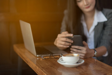 Young female freelancer checking email on cell during coffee break. Business concept.