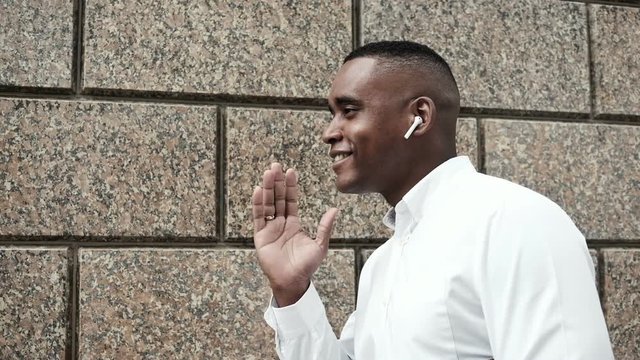 Handsome young businessman using smartphone smiling happy. African american man talking on the phone using wireless earphones in city. Series of business people - interns, financial advisors, CEO