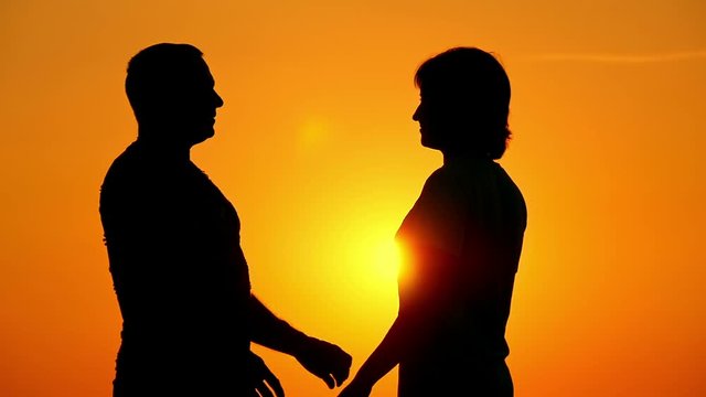 woman and a man go to each other, kiss at sunset.