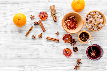 Hot mulled wine or grog cooking for new year celebration with oranges and spices ingredients on light background flat lay mockup