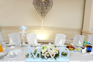 Stół weselny z bukietem róż, miejsce dla pary młodej.