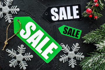 Winter sale. Sale labels near spruce branches on black background top view
