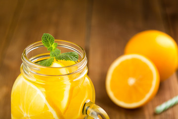 Detox water with orange slices in a glass jar with a handle close-up.