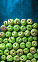Green and red large colorful group of organic apples overhead on rustic blue table in studio