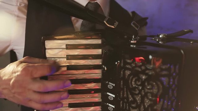A fashionable musician in a white shirt plays the accordion in the studio.
