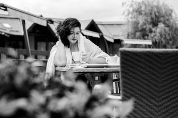 Mature stylishly dressed woman, dark hair eating breakfast tasty sweet cake in a cafe drinking coffee . The beauty of the city's morning. The concept of harmony and life in a big city