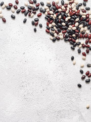 Top view of raw mixed beans on gray concrete background. Mixed of uncoocked black, red and white beans with copy space. Fodd background. Vegan protein concept.