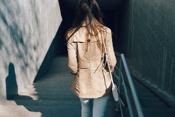 Woman in a beige jacket and jeans descends into the underpass