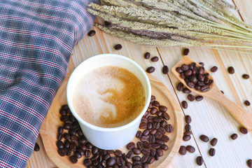 Paper latte art coffee cup and beans on wood table decorate with cloth. 