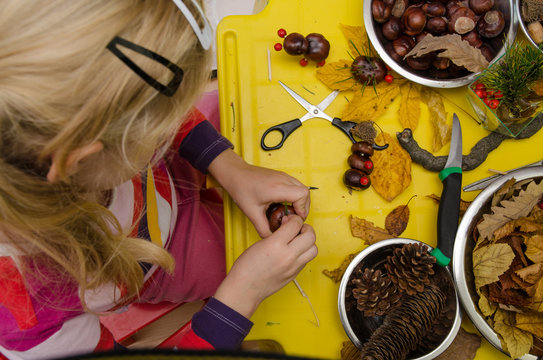 little child creating autumn decorations