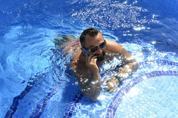 El hombre esta en la piscina hablando por telefono
