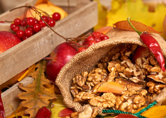 Nuts in a sack, fruits and vegetables on fallen leaves background, autumn season