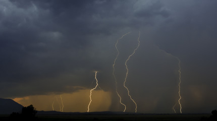Cloudy sky with visible lightnings while raining at mountain landscape
