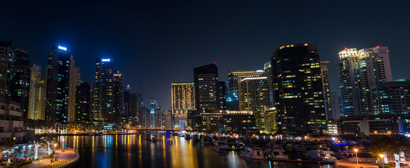 Fototapeta na wymiar Panorama of illuminated skyscrapers with reflection in water night