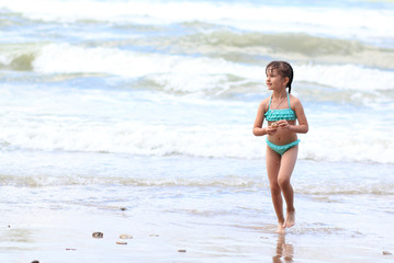 Fototapeta premium The small beautiful girl with plaits in a turquoise bathing suit on seacoast