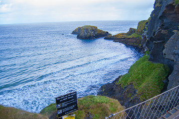 Ballintoy, United Kingdom - May 2, 2016: Carrick-a-Rede Rope Bridge, a popular tourist destination in Northern Ireland. Tourists passing the bridge.