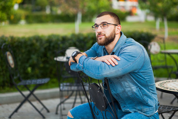 Confident young man in a street cafe