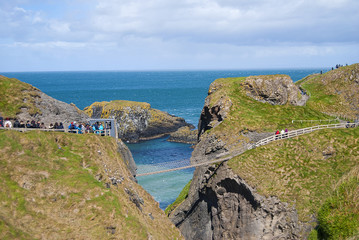 Ballintoy, United Kingdom - May 2, 2016: Carrick-a-Rede Rope Bridge, a popular tourist destination in Northern Ireland. Tourists passing the bridge.