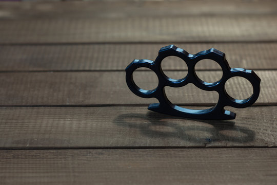 Brass knuckles on a beautiful brown wooden background. Stock Photo
