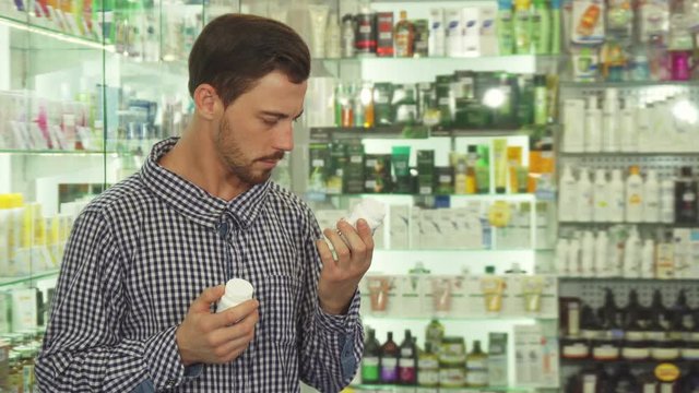 Man reading packaging of two drugs. He is hesitating which to choose. Patient is in drugstore