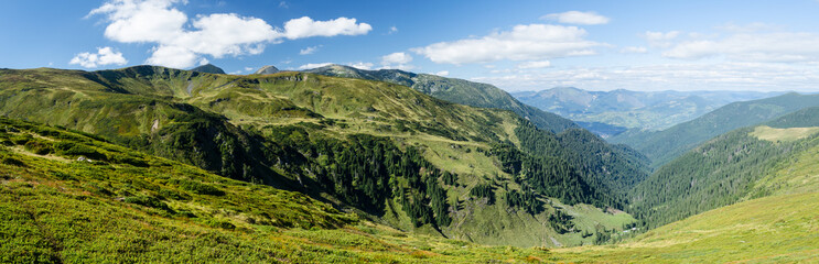 Panoramic view of mountain ridges with a village in the background in sunny summer day