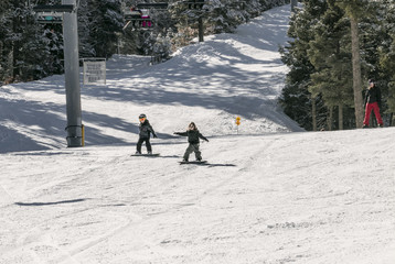 boys snowboarding down a big hill at a ski resort 